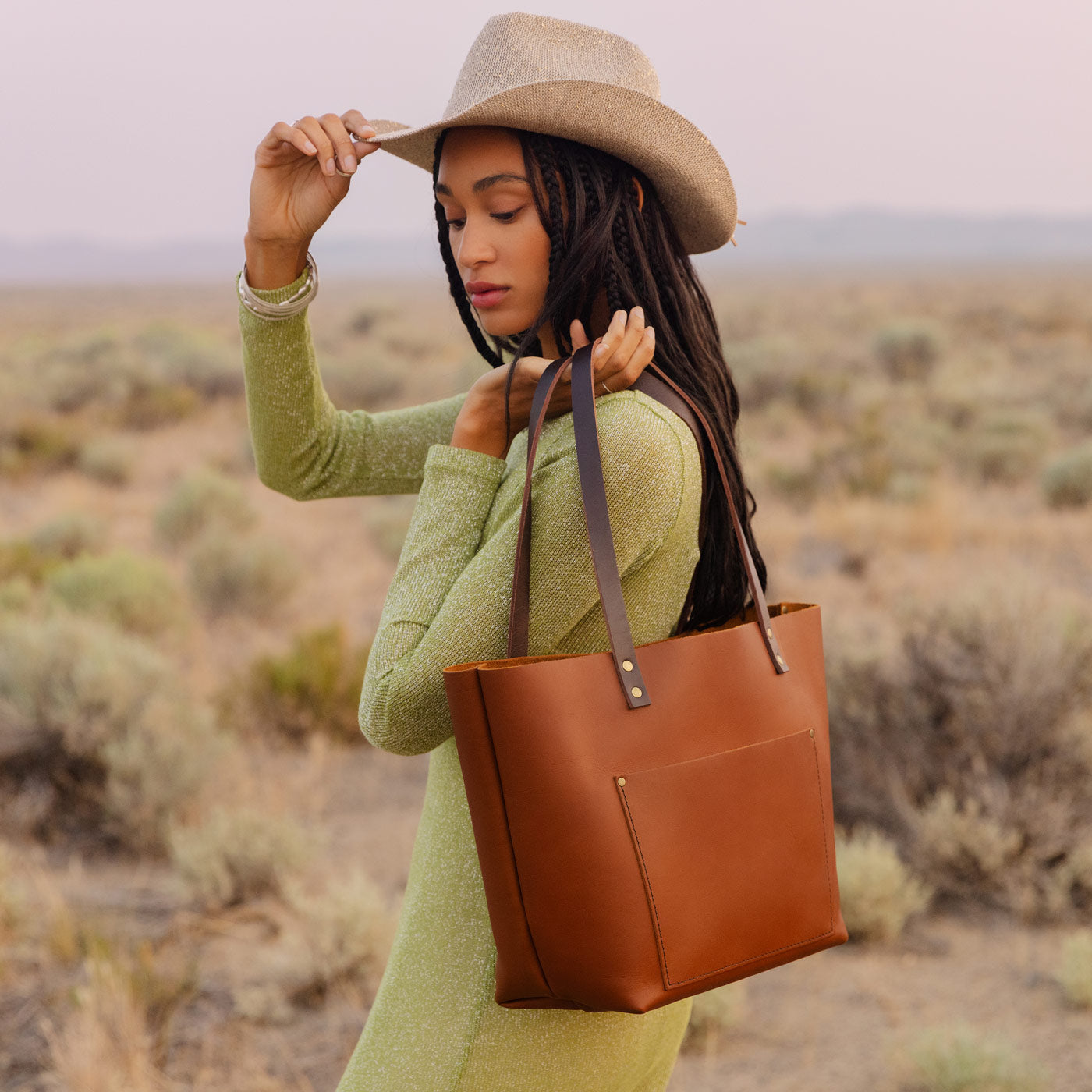 Honey*Classic | Model holding large leather tote bag with sturdy bridle handles and front pocket