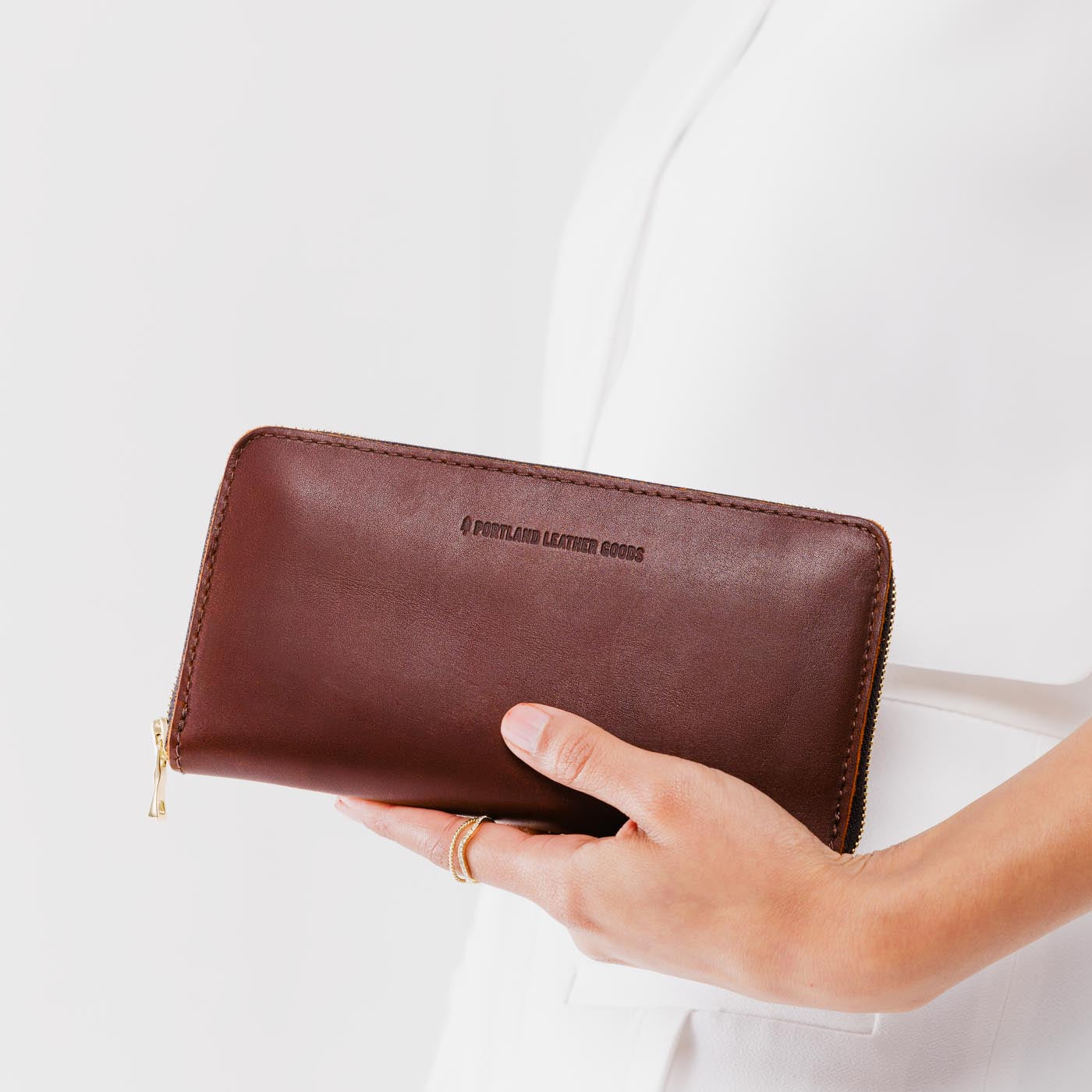 Cognac | Model holding large accordion leather wallet with zipper closed