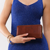 Nutmeg | Model holding large accordion leather wallet with zipper closed