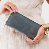 Storm | Model holding flowers and large accordion leather wallet with zipper closed