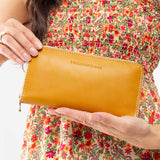 Sunflower | Model holding large accordion leather wallet with zipper closed