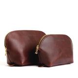 Cognac | Size comparison shot of leather makeup bags with curved top zipper and flat bottom