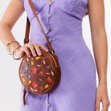 Folklore Nutmeg Small | Circle shaped crossbody bag with embroidered flower design