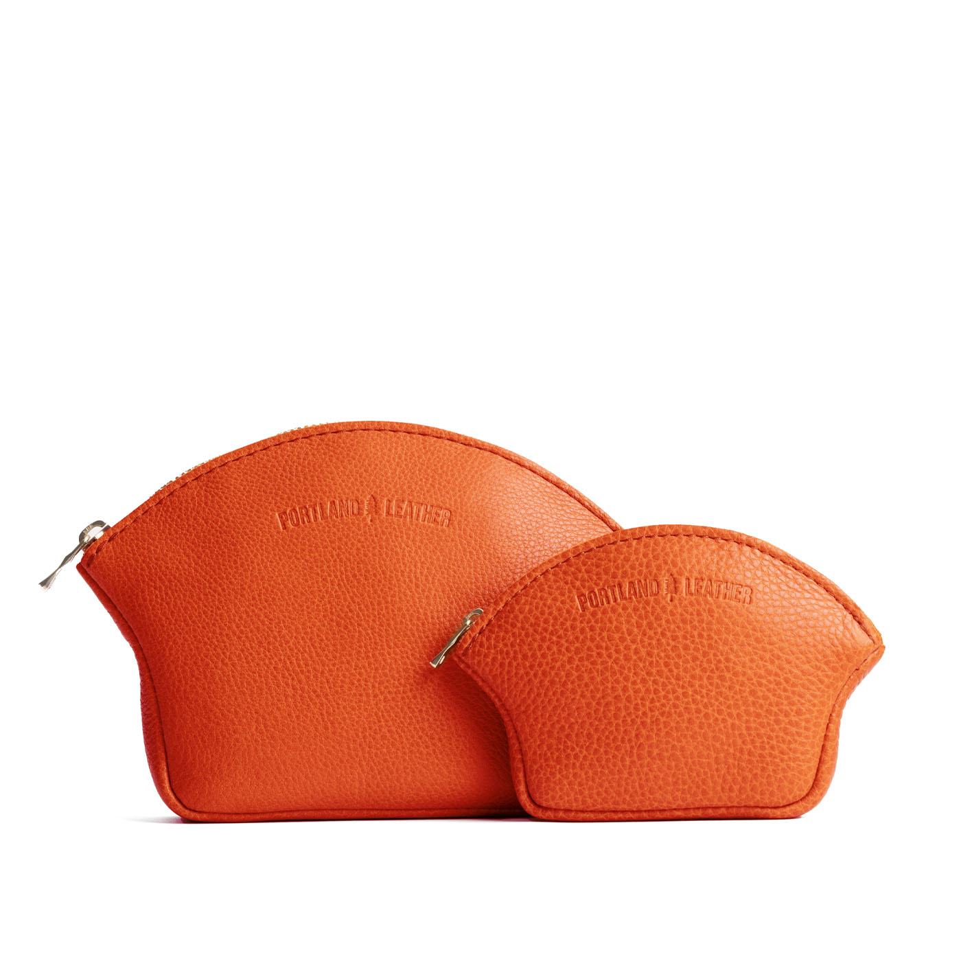 Koi | Comparison shot of small and large seashell shaped leather makeup bags with curved top zipper and flat bottom