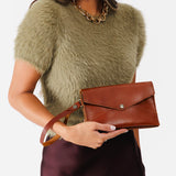 Chestnut | Model wearing envelope shaped clutch wallet with crossbody strap