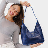 Cowboy Blue | Model holding structured hobo shoulder bag with adjustable strap and magnetic closure