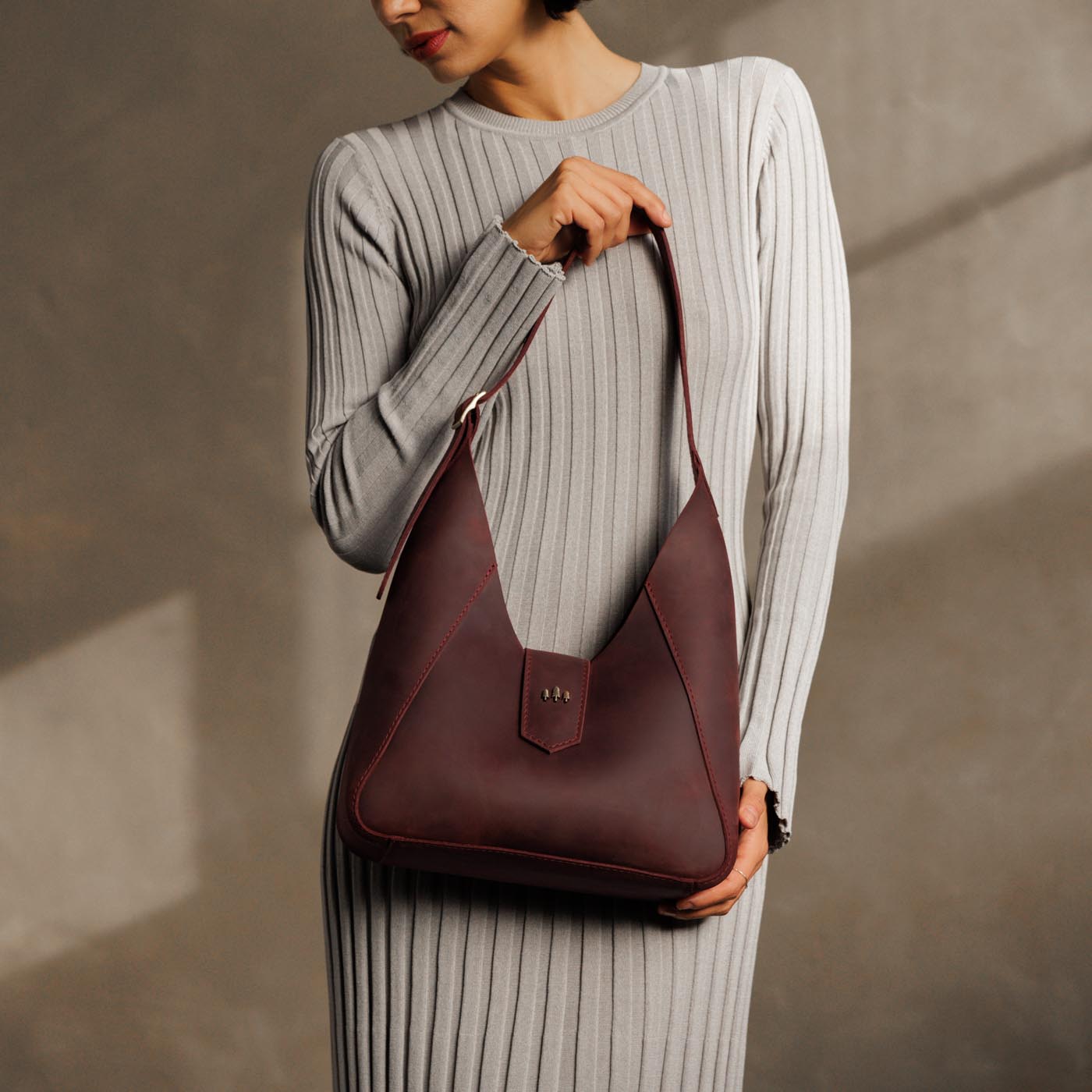 Merlot | Model holding structured hobo shoulder bag with adjustable strap and magnetic closure