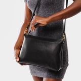 Pebbled--black | Model wearing midsize zip top crossbody bag with detachable strap