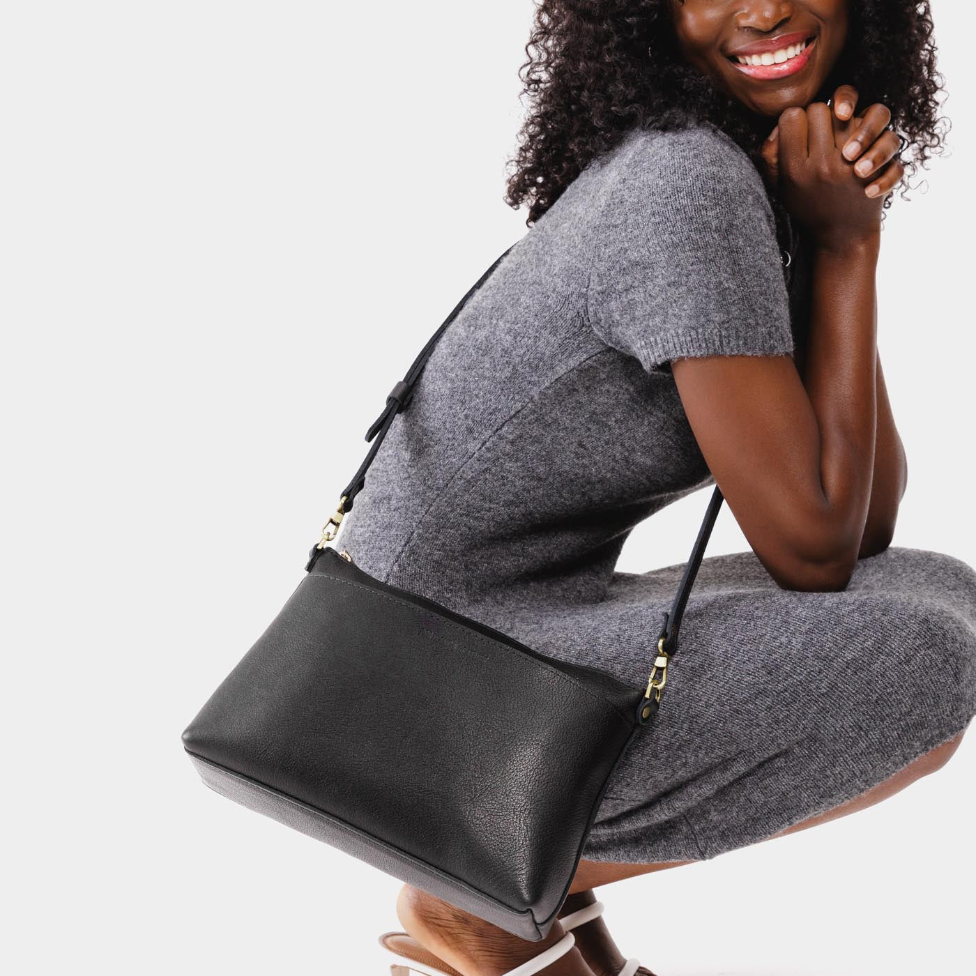 Pebbled--black | Model holding midsize zip top crossbody bag with detachable strap