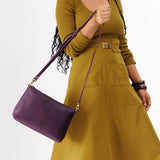 Plum | Model holding midsize zip top crossbody bag with detachable strap