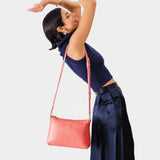 Watermelon | Model holding midsize zip top crossbody bag with detachable strap