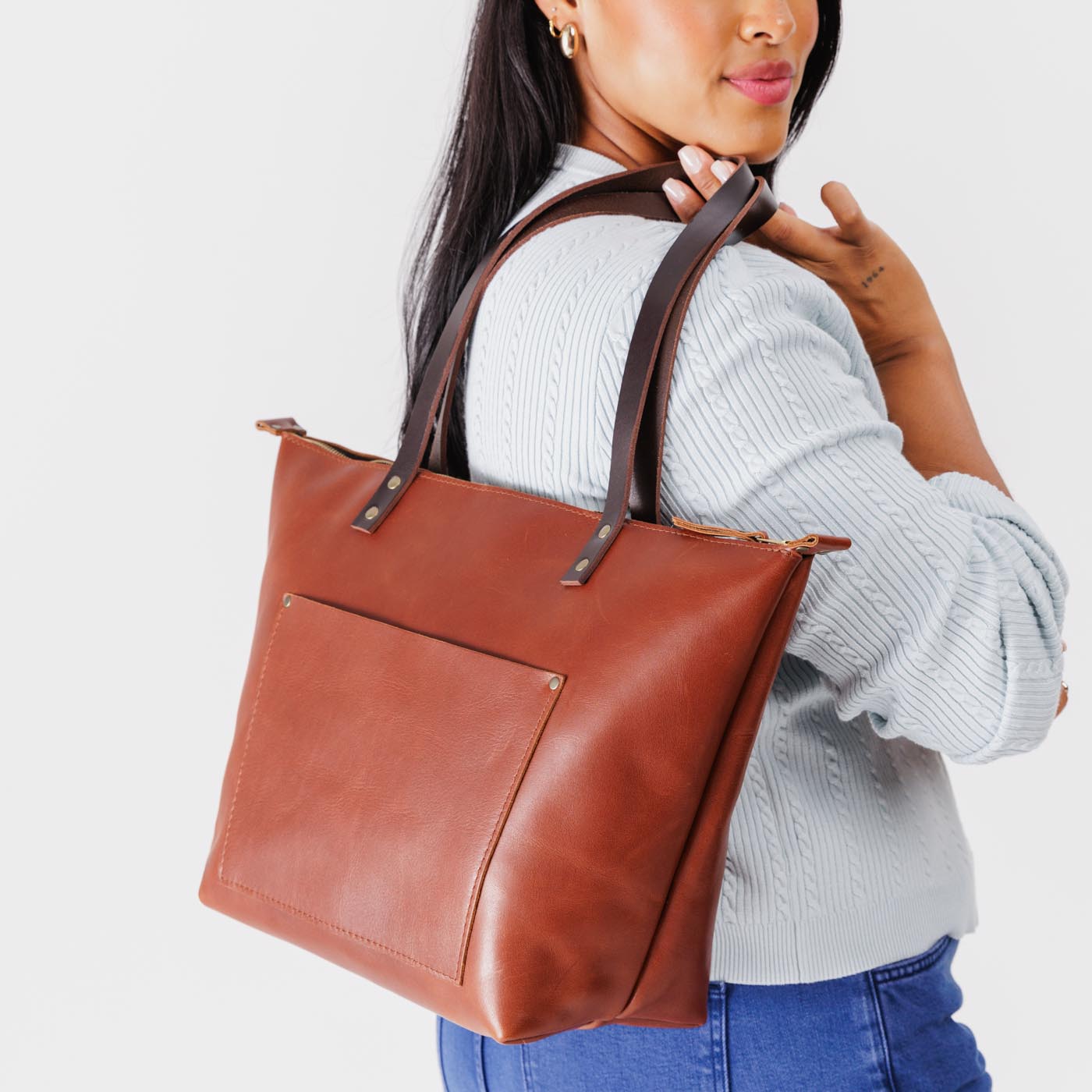 Chestnut*Zipper | Model holding large leather tote bag with sturdy bridle handles and front pocket