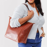 Chestnut Zipper | Model holding large leather tote bag with sturdy bridle handles and front pocket