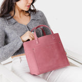 Foxglove Classic | Model holding midsize crossbody tote with handles and a pocket