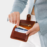 Nutmeg | Model holding small leather bifold wallet with snap open