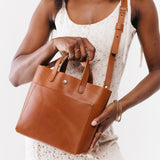 Honey Classic | Model holding crossbody tote bag with snap closure and front pocket