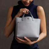 Formal Grey Classic | Model holding crossbody tote bag with snap closure and front pocket