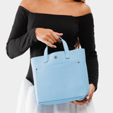 Glacial Blue Classic | Model holding crossbody tote bag with snap closure and front pocket