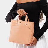 Mamey Classic | Model holding crossbody tote bag with snap closure and front pocket