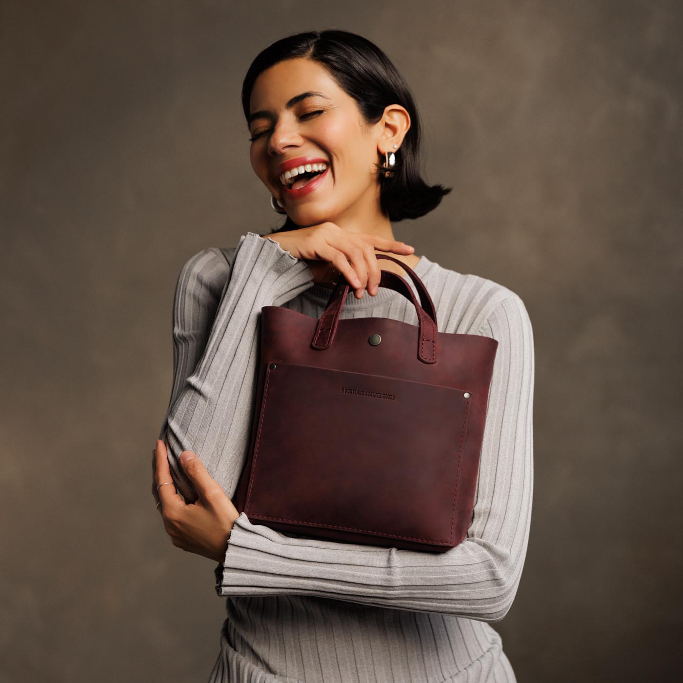 Merlot*Classic | Model holding crossbody tote bag with snap closure and front pocket