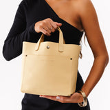 Vanilla Classic | Model holding crossbody tote bag with snap closure and front pocket