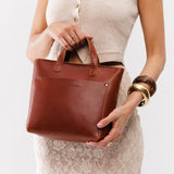 Chestnut Zipper | Model holding crossbody tote bag with zipper closure and front pocket