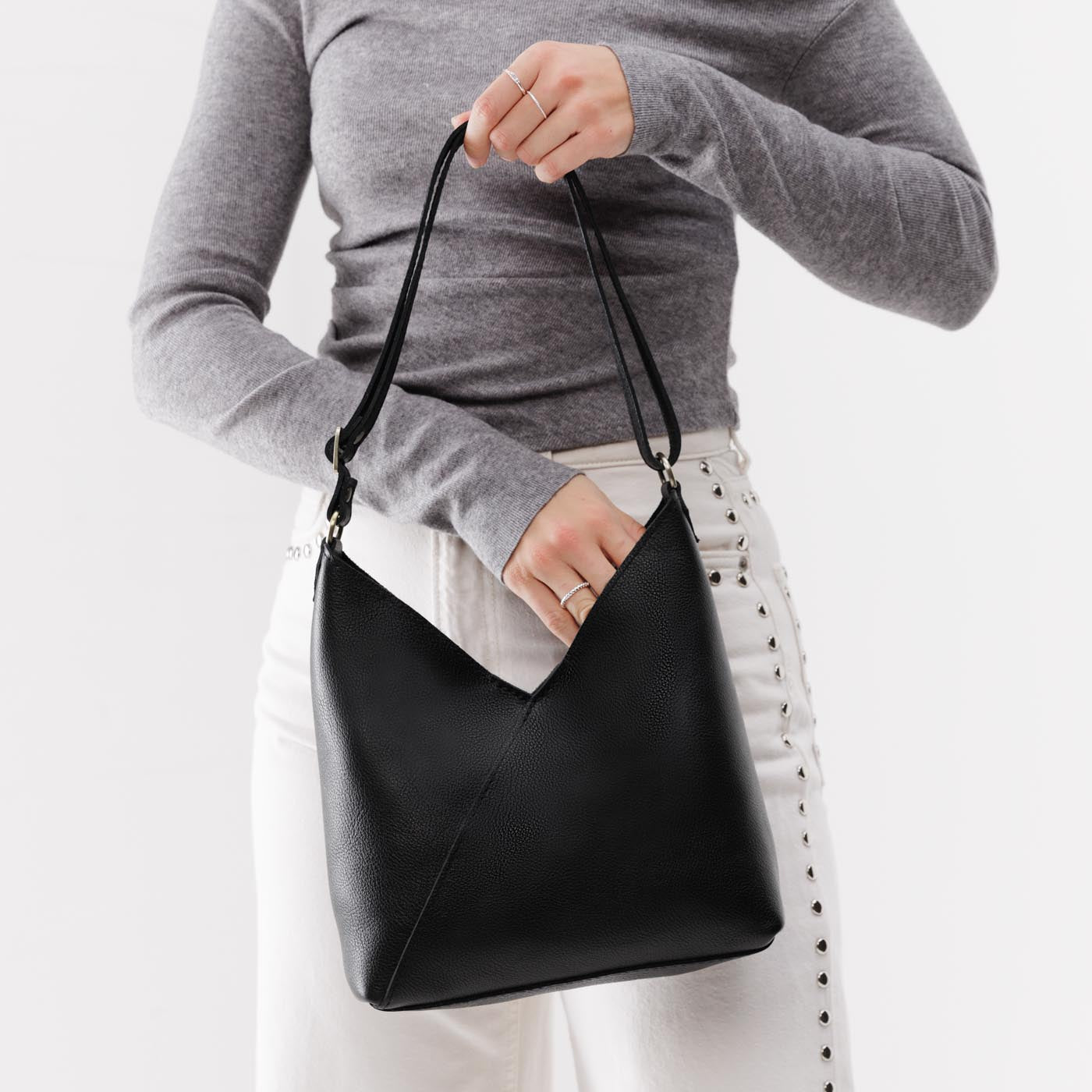 Pebbled--black*Small | Model holding petite shoulder bag with adjustable strap and magnetic snap closure