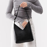 Pebbled--black Small | Model holding petite shoulder bag with adjustable strap and magnetic snap closure