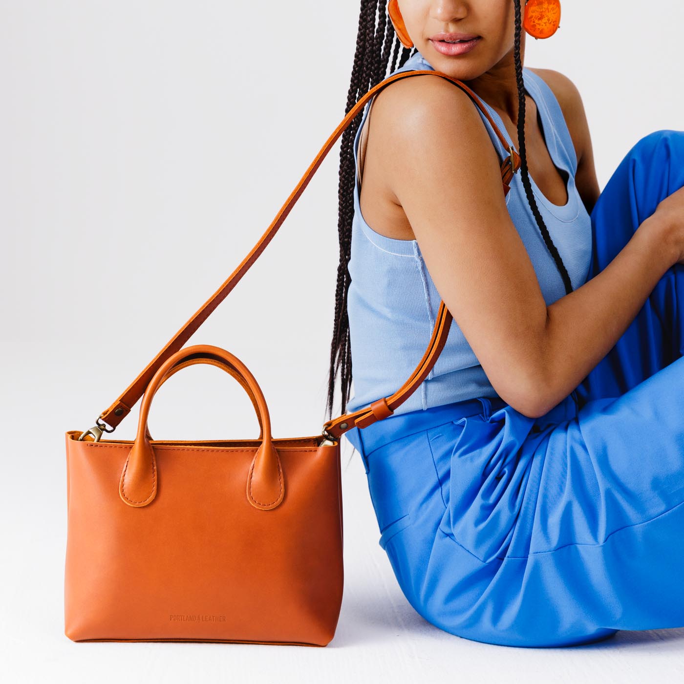 Tuscany*Large | Model holding mid-size tote purse with  structured leather handles and crossbody strap