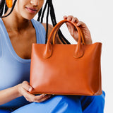 Tuscany Large | Model holding mid-size tote purse with  structured leather handles and crossbody strap