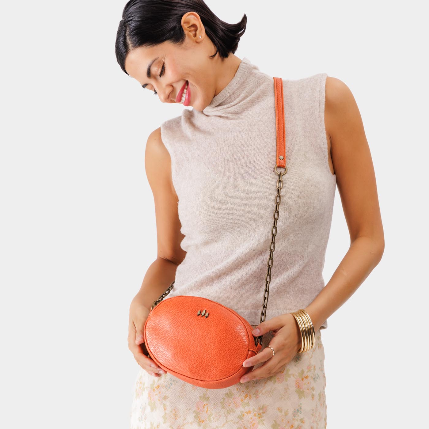 Koi | Model wearing oval leather purse with metal crossbody chain strap and adjustable leather shoulder guard