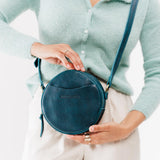 Lagoon Small | Model holding circle shaped crossbody bag with top zipper