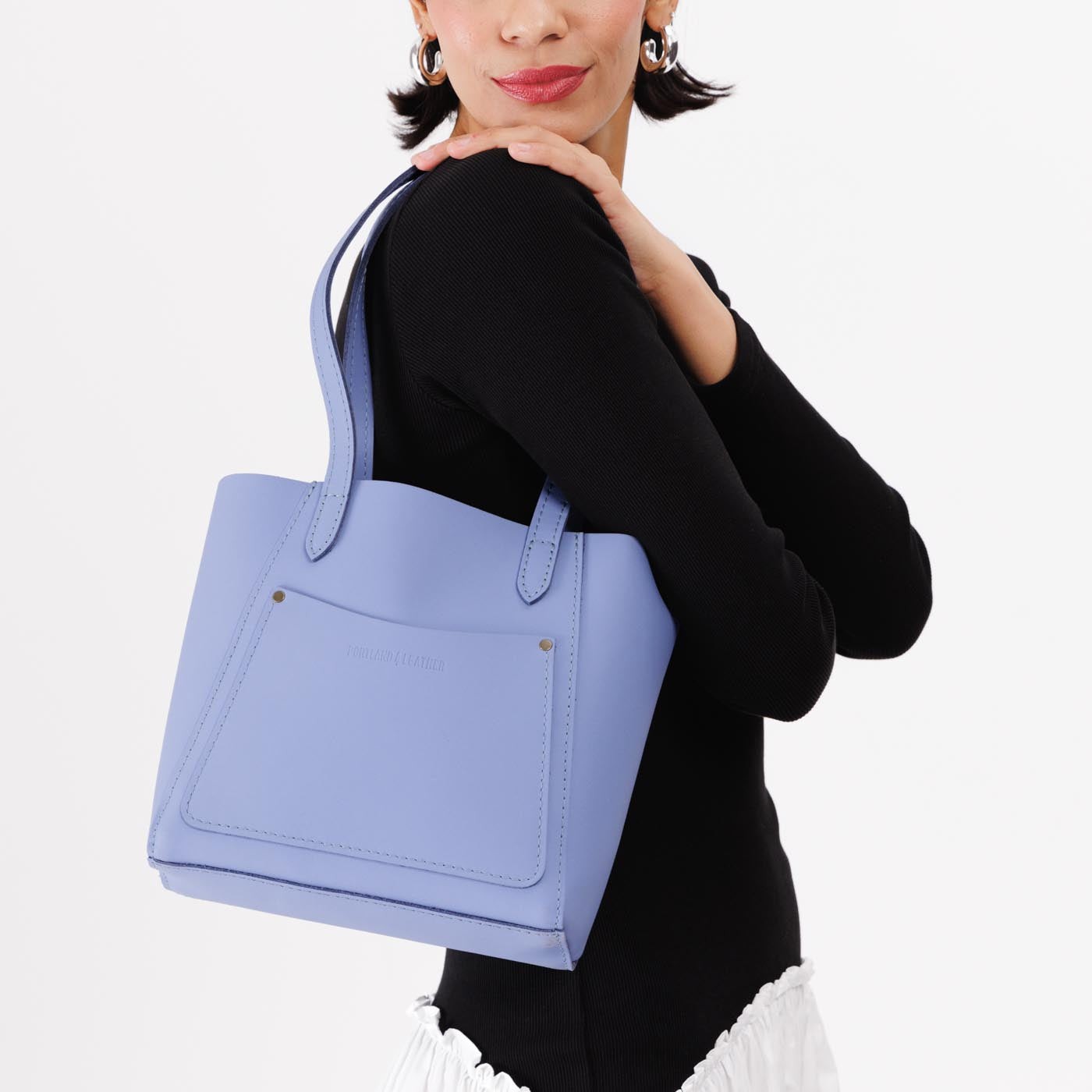 Jacaranda*Small | Model holding dual shoulder strap tote bag with an exterior pocket