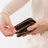 Nutmeg | Model holding small leather wallet with zipper open