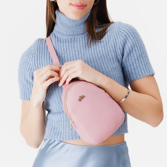 Vintage Pink | Model wearing small sling bag with zipper closure and adjustable strap on the front of her body