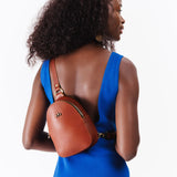 Chestnut | Model wearing small sling bag with zipper closure and adjustable strap