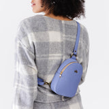 Jacaranda | Model wearing small sling bag with zipper closure and adjustable strap