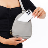 Nimbus | Model holding small sling bag with zipper closure and adjustable strap