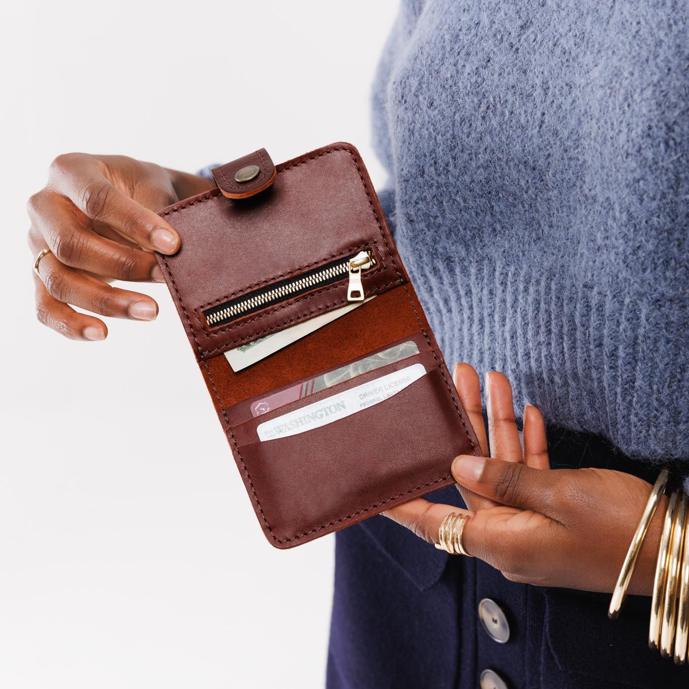 Cognac | Model holding small leather bifold wallet with snap open