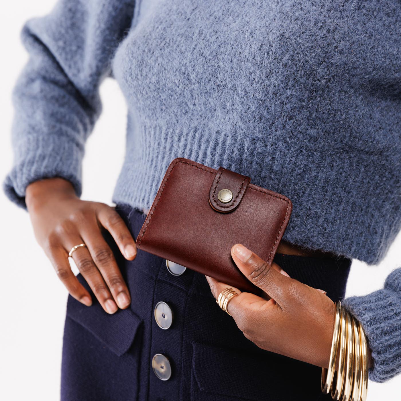 Cognac | Model holding small leather bifold wallet with snap closed