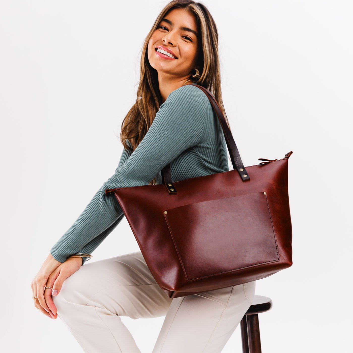 Cognac*Zipper | Model holding large zipper leather tote bag with sturdy bridle handles and front pocket