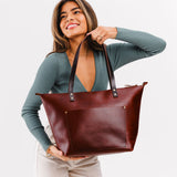 Cognac Zipper | Model holding large zipper leather tote bag with sturdy bridle handles and front pocket