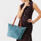 Aqua Zipper | Model holding large leather tote bag with sturdy bridle handles and front pocket