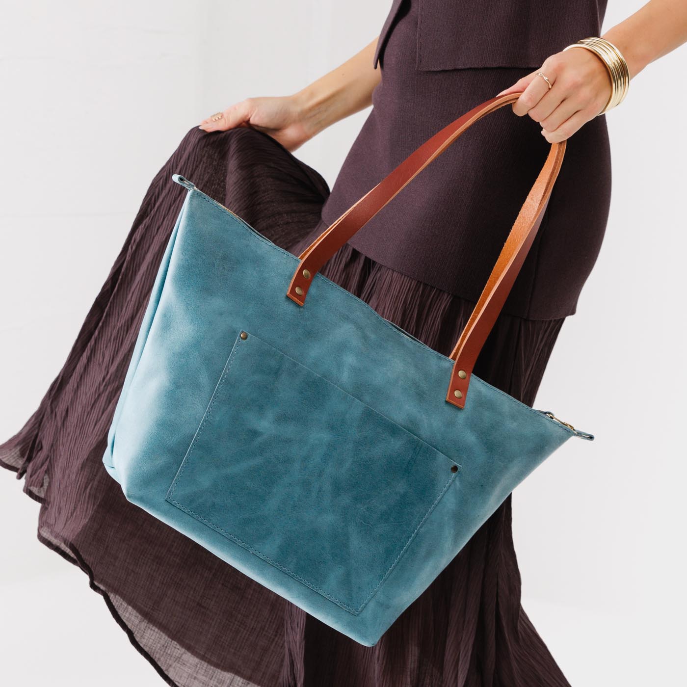 Aqua*Zipper | Model holding large leather tote bag with sturdy bridle handles and front pocket