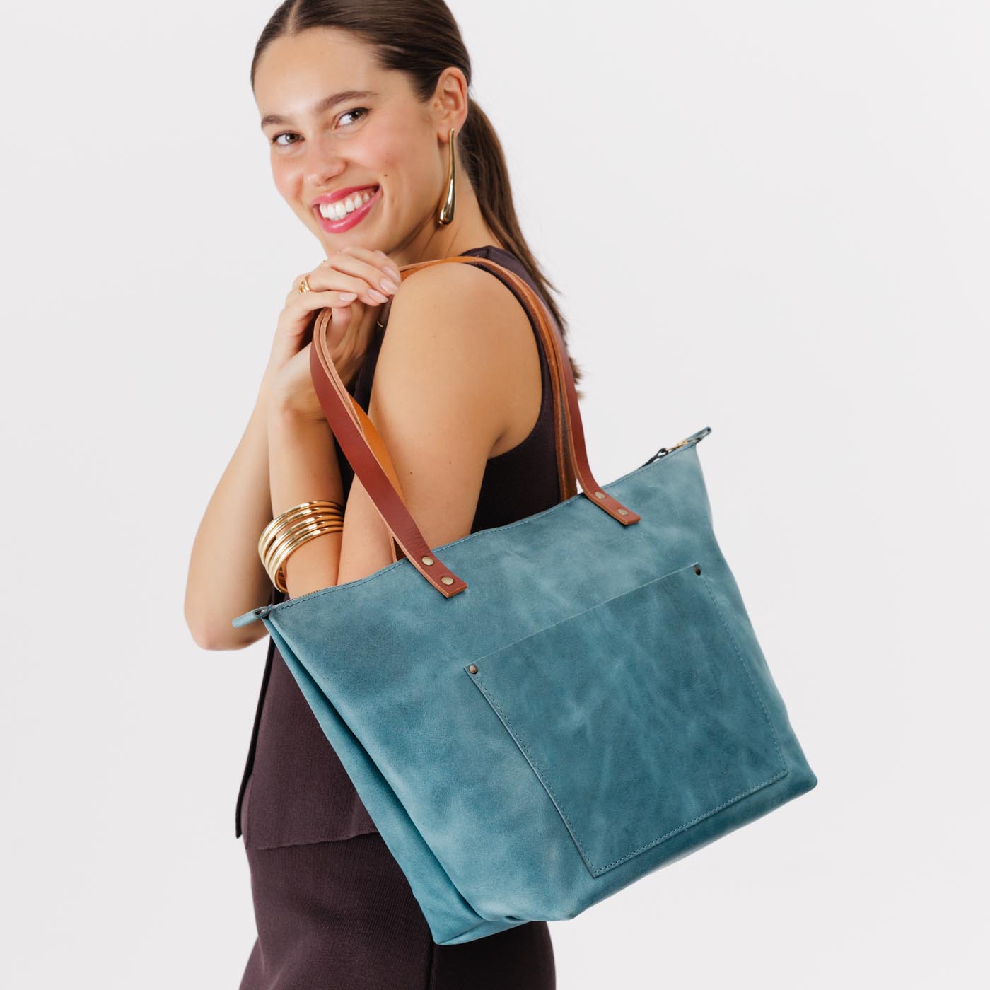 Aqua*Zipper | Model holding large leather tote bag with sturdy bridle handles and front pocket